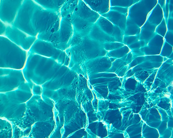 Bright turquoise water surface in sunlight, capturing shimmering patterns and reflections.