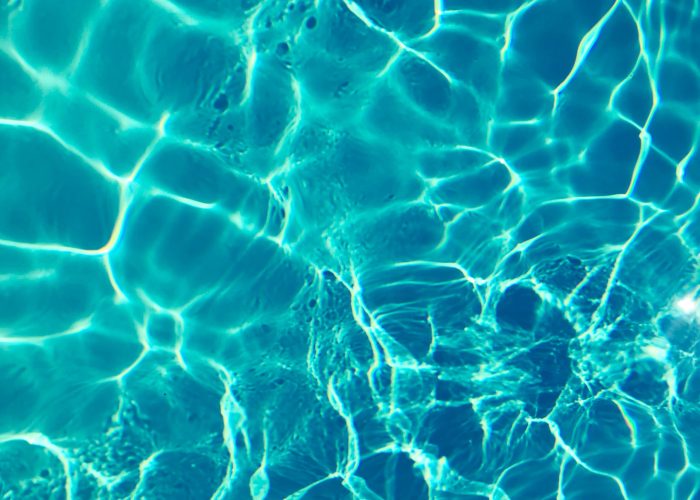 Bright turquoise water surface in sunlight, capturing shimmering patterns and reflections.