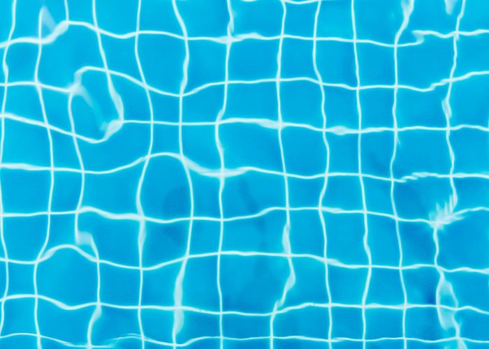 Top view of a swimming pool with vibrant blue water and tile patterns.