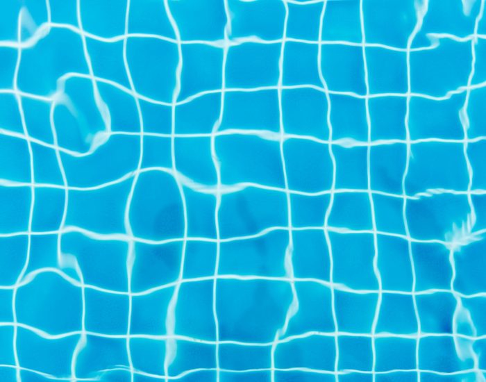 Top view of a swimming pool with vibrant blue water and tile patterns.